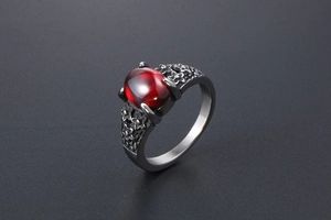 Detail of vintage stainless steel ring with red gemstone and floral engravings