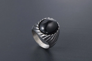 Macro view of men's vintage titanium steel ring with oval black agate and striped texture