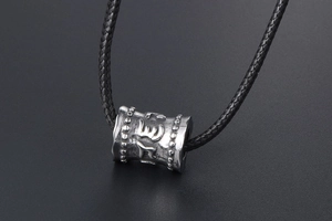 Vue macro d'un pendentif mantra en acier titane avec relief vintage et cordon tressé