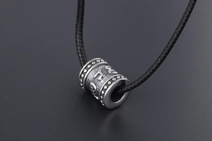 Detailed view of titanium steel cylinder pendant with embossed Buddhist Mantra characters