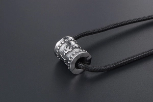 Vue macro du pendentif cylindre mantra bouddhiste en acier titane avec finition vintage