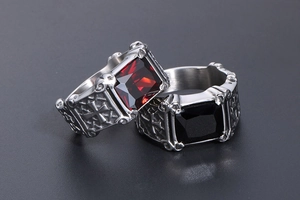 Macro shot of gothic steel rings with red and black gems and side cross engraving
