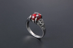 Macro view of vintage stainless steel ring featuring red gemstone and floral engravings