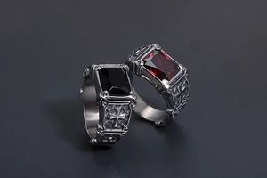 Close-up of Gothic cross rings with red and black rectangular gemstones in steel