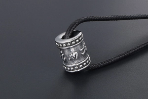 Macro view of vintage titanium steel cylinder pendant with embossed Buddhist mantras