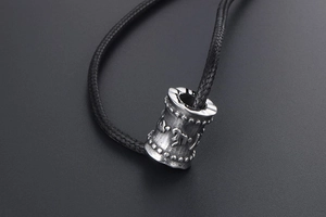 Détail macro du pendentif mantra en argent vintage avec corde tressée noire et gravures