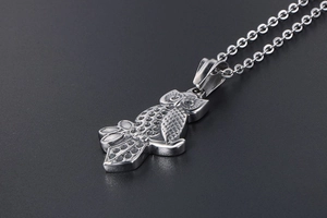 Macro shot of silver owl pendant with crystal embellishments on textured background
