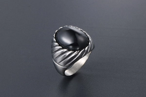Close-up of vintage titanium steel ring featuring an oval black agate stone and striped texture