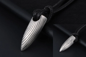 Détail macro du pendentif balle en acier inoxydable avec cordon tressé noir