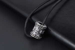 Macro shot of titanium steel cylinder pendant with engraved Sanskrit Six-Word Mantra detail