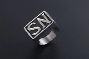 Macro detail of men's stainless steel signet ring with embossed SN letters and black texture