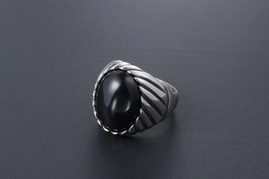 Macro view of vintage men's steel ring with black oval stone and textured engraving