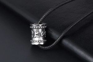 Vue macro d'un pendentif cylindre en titane avec mantra embossé sur cuir noir