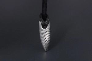 Vue macro d'un pendentif balle industriel avec rainures en spirale et cordon noir