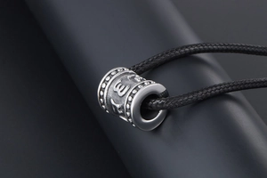 Macro shot of vintage titanium steel cylinder pendant with embossed religious symbols