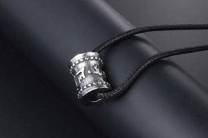 Détail du pendentif cylindre en acier titane avec écriture en relief et cordon