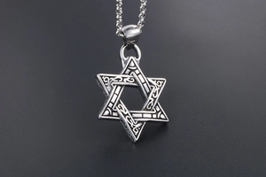 Detail of vintage silver hexagram pendant with Celtic engravings and stainless steel chain