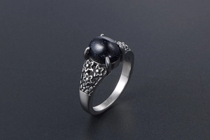Macro side view of vintage stainless steel ring with blue goldstone and floral carving