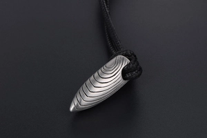 Vue détaillée du pendentif balle avec texture rainurée et cordon en tissu noir tressé