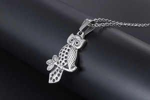 Macro shot of silver stainless steel owl pendant showing detailed feather textures