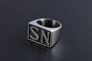 Detail of masculine steel signet ring with embossed SN letters and brushed metal finish