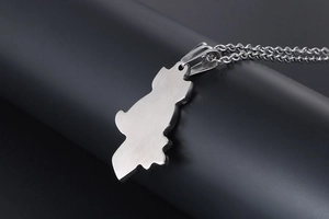 Macro detail of silver owl silhouette pendant with brushed metal texture and link chain