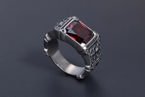 Macro view of gothic steel ring with deep red gemstone and side cross engravings