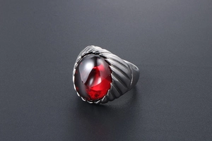 Close-up of vintage titanium steel ring featuring a red oval agate with textured detailing