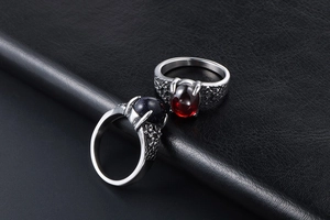 Detailed close-up of vintage steel rings with red and blue gemstones on floral relief