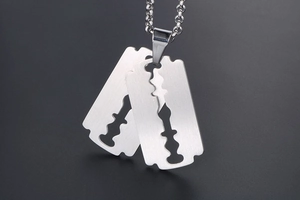 Close-up of dual razor blade pendant with brushed stainless steel finish on black background