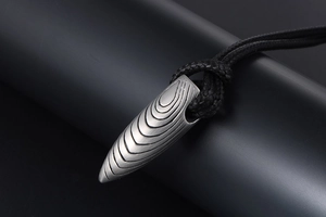 Gros plan d'un pendentif en forme de balle avec finition gris mat et lignes circulaires