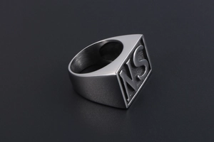 Detailed macro shot of a silver stainless steel signet ring featuring embossed NS letters
