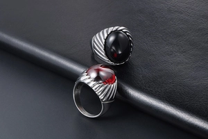 Close-up of vintage steel rings with red and black agate on black leather background