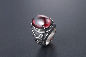 Macro shot of men's eagle relief ring with deep red oval gemstone inlay