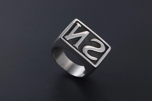 Macro shot of silver signet ring with embossed NS letters on matte textured background