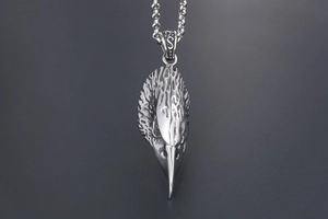 Macro detail of silver-toned vintage eagle head pendant with intricate feather texture