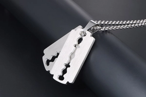 Detailed close-up of a silver stainless steel razor blade pendant on a black prop