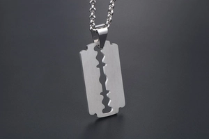 Macro shot of a razor blade pendant in brushed stainless steel on a bead chain