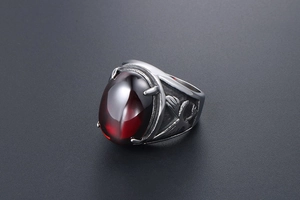 Macro shot of men's vintage steel ring with red oval stone and eagle relief details