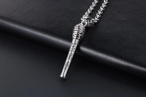 Macro detail of silver microphone pendant with Chinese engraving on black leather background