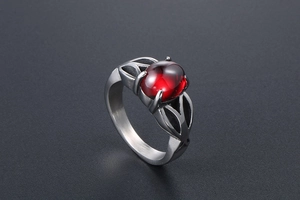 Detailed close-up of a vintage stainless steel ring with a red oval gemstone and leaf motifs