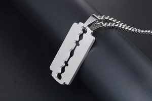 Macro shot of stainless steel razor blade pendant with brushed metal texture on bead chain