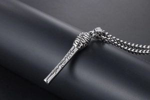 Macro detail of the silver cylinder pendant with intricate engravings and bead chain link