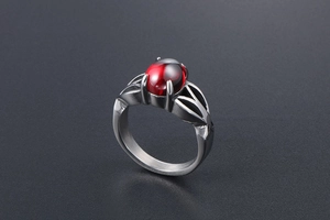 Detail of vintage stainless steel ring with oval red gemstone and leaf cutout design