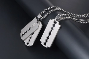 Macro shot of silver razor blade pendant with brushed matte texture and rolo chain necklace