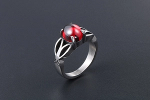 Macro shot of vintage stainless steel ring with a red oval gemstone and leaf detail