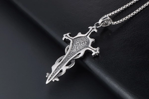 Macro detail of gothic cross pendant with serpent motif in polished stainless steel