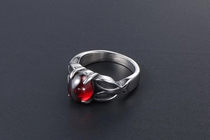 Detailed close-up of retro stainless steel ring with oval red gemstone inlay on black surface