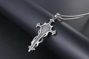 Macro detail of gothic sword pendant with snake relief on a stainless steel box chain