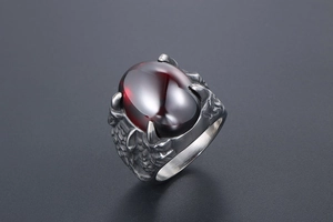 Détail d'une bague griffe de dragon rétro ornée d'une grande pierre rouge ovale foncée
